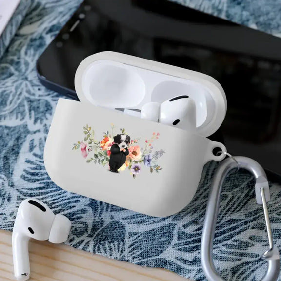 Custom AirPods case with pet face design, featuring a floral background, lying on a table with earbuds and a smartphone nearby.