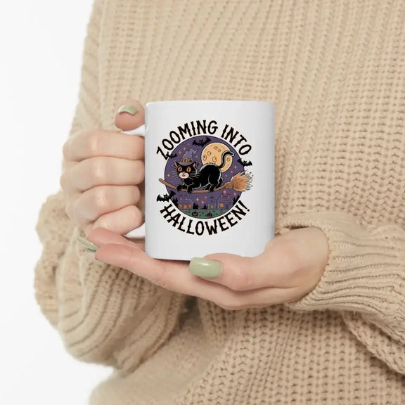 Woman holding personalized Halloween ceramic mug with black cat design and "Zooming into Halloween" text.