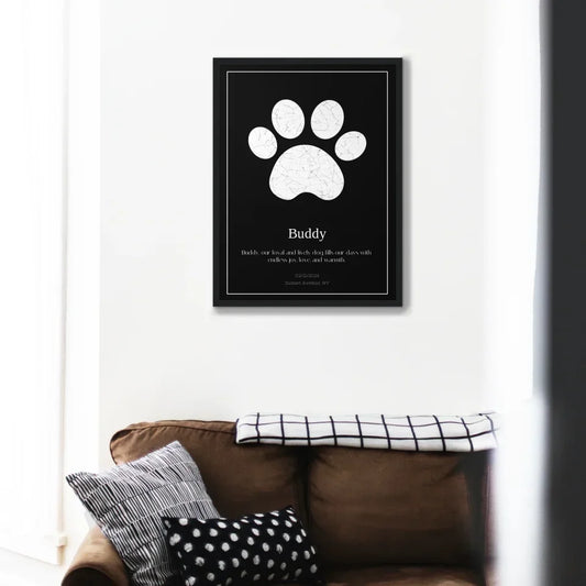 Custom Paw Print Star Map memorial framed on a wall above a couch, a tribute to a pet with a starry sky design.