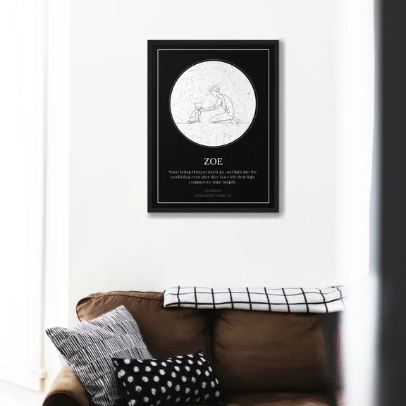 Personalized cat memorial star chart on a wall above a couch, featuring a tribute to a beloved pet named Zoe.