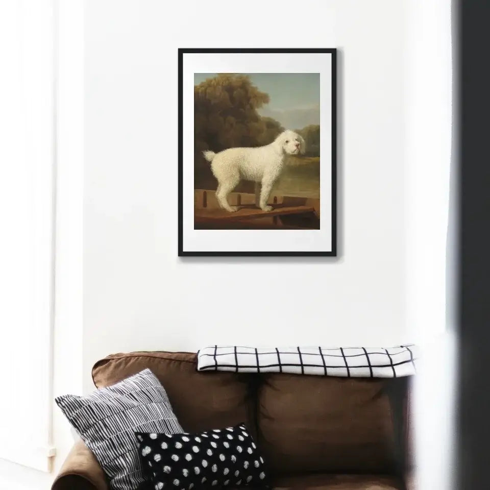 Victorian art print of white poodle in a boat, framed and displayed above a couch, adding elegance and charm to home decor.