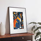 Colorful Matisse-inspired cat art print in a black frame on a table, featuring vibrant hues and bold lines for a modern home decor touch.