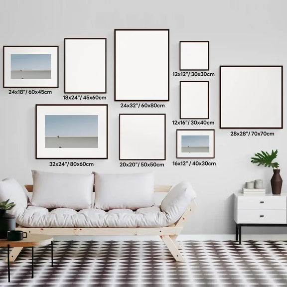 Art prints wall display of various sizes above a modern sofa, featuring minimalist decor in a stylish living space.