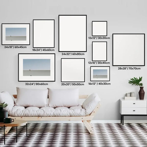 Gallery wall display with multiple blank picture frames on a modern living room wall above a white couch with cushions.