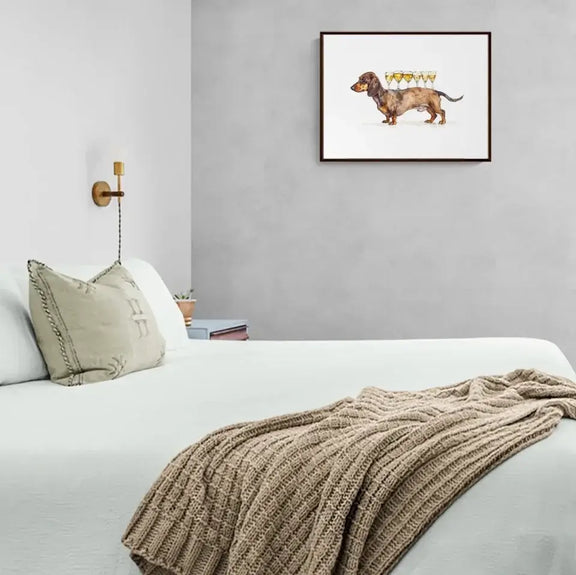 Charmingly framed dachshund art print in minimalist bedroom, adding warmth and whimsy to decor. Perfect for dog lovers and cozy spaces.